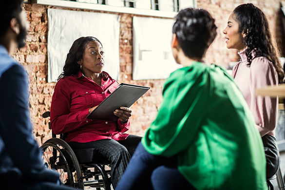 Businessperson in wheelchair leading group discussion in an office