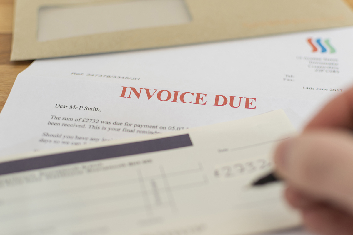 Someone writing a cheque to pay an invoice.