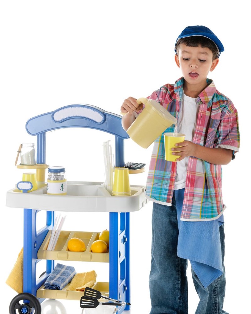 A child with a lemonade stand, pouring lemonade into a cup