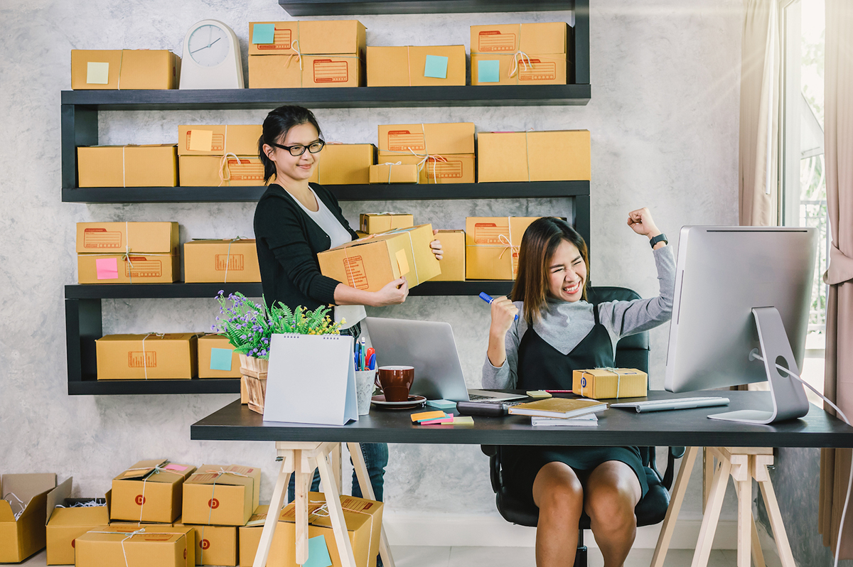 Two businesspeople in an office setting with one carrying a box and one making a celebratory gesture
