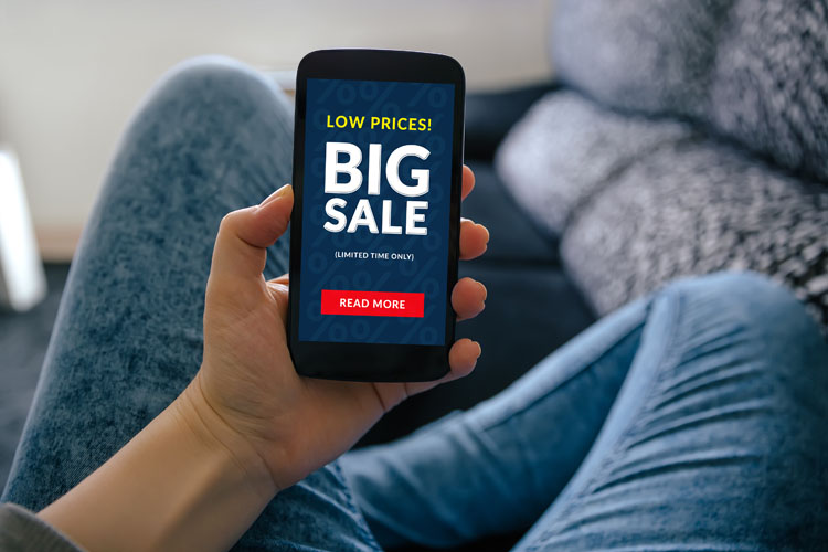 A person holding a smartphone showing a sale advertisement