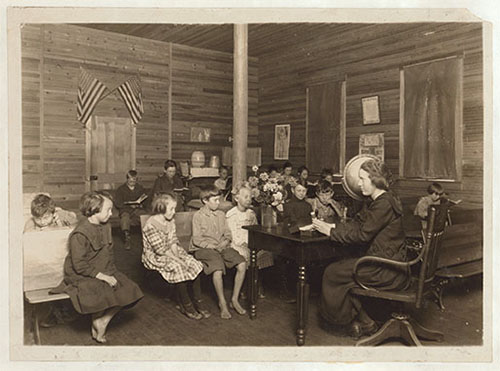 Students sitting in rows while a teacher teaches at the front of the class