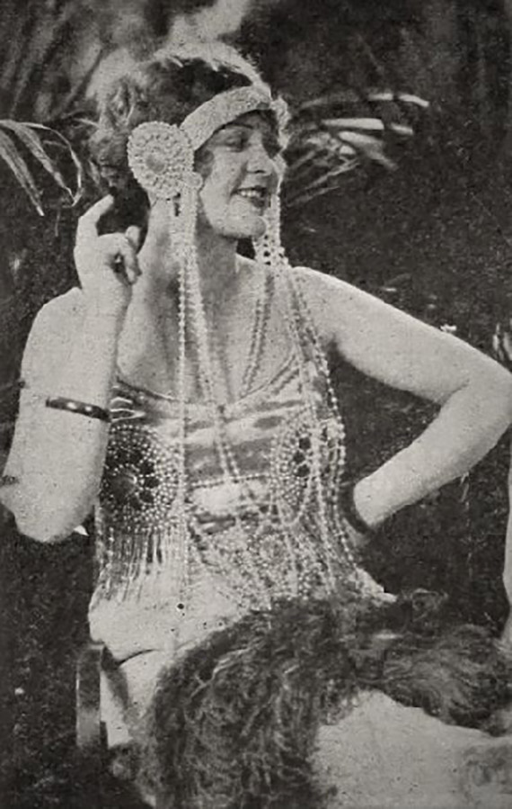 A picture of a typical flapper from 1924. A woman wearing a flowy dress and headdress with several beads hanging down.