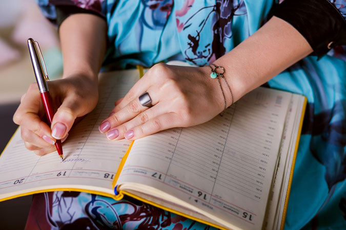 A person writing in a day planner.