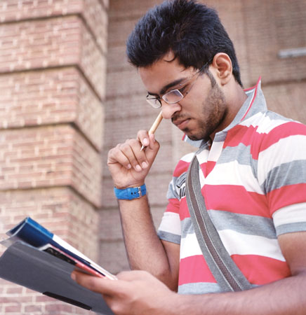 A student holding a pen and books.