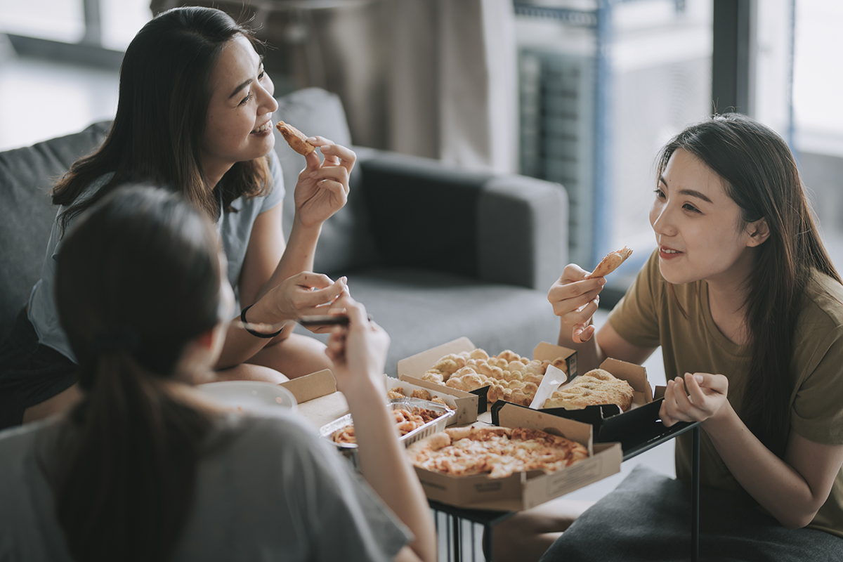 Three friends eating pizza in a living room