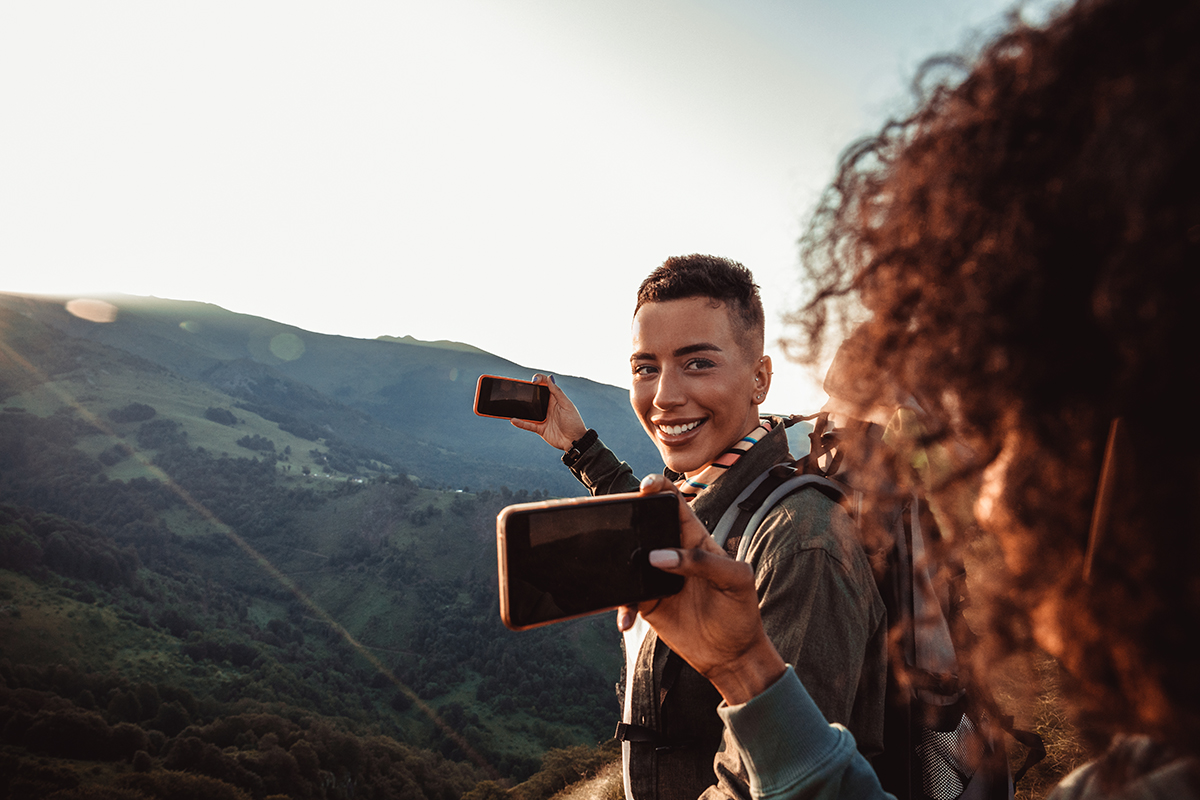 Two hikers taking photos of a sunset