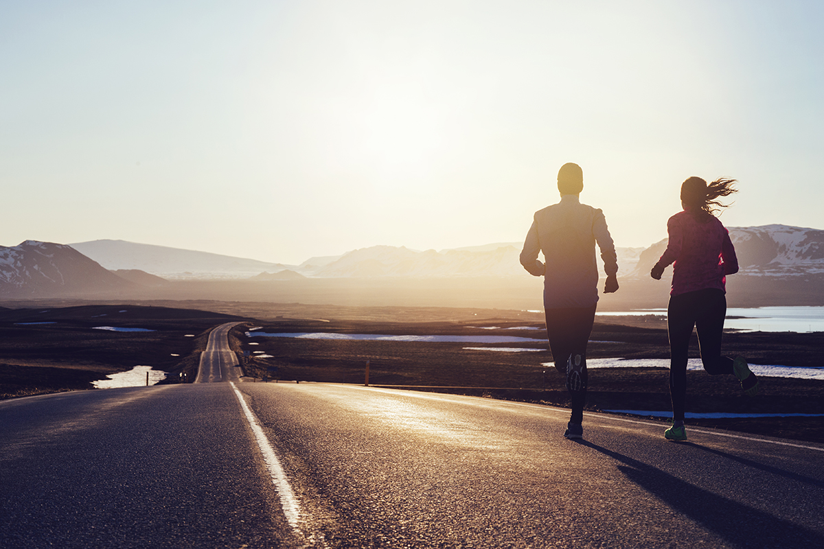 A couple running along a road as the sun rises