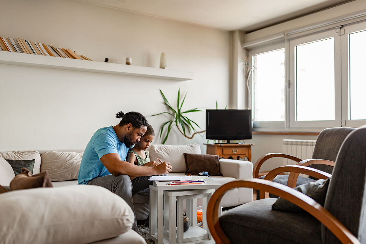 A parent helping a child with homework in the living room