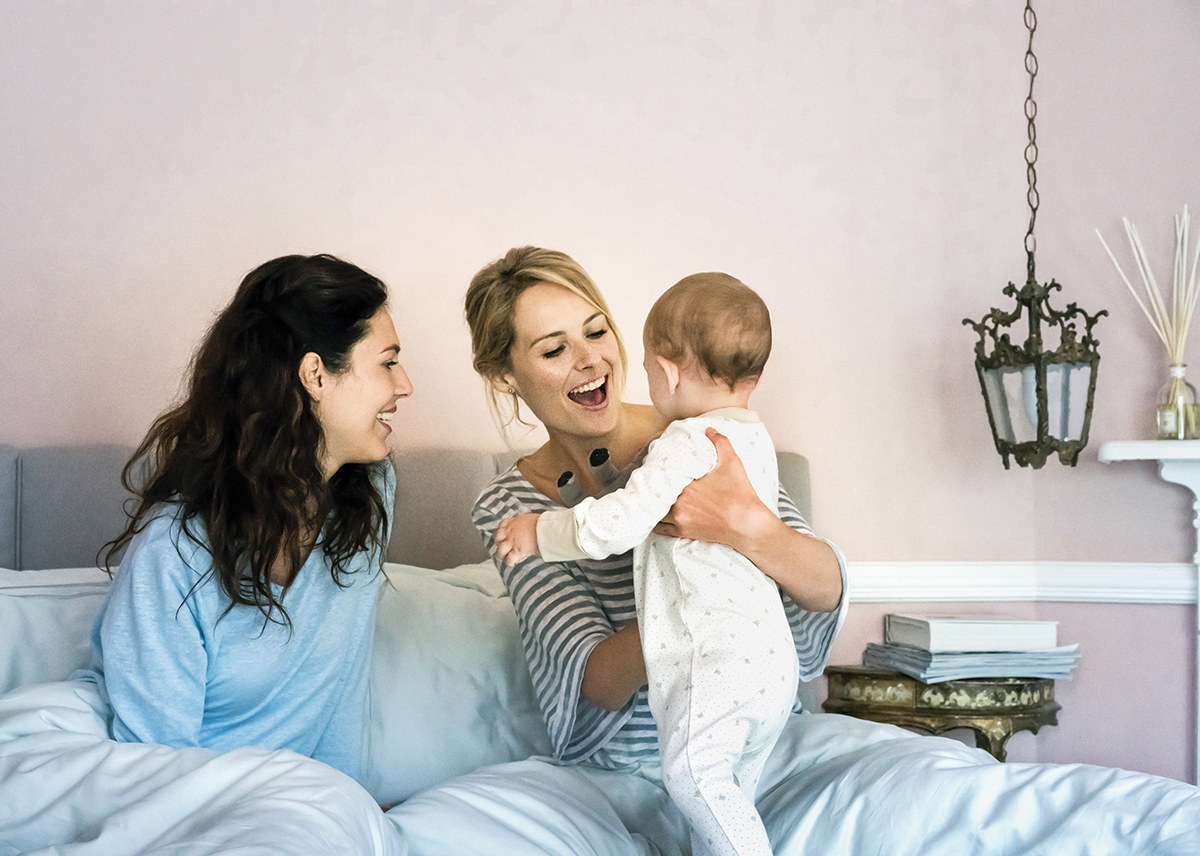 parents playing with their baby in bed