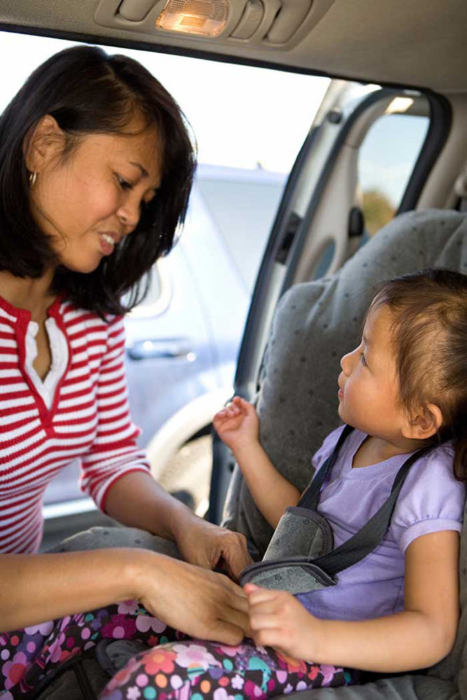 Mother buckling her child into a car seat