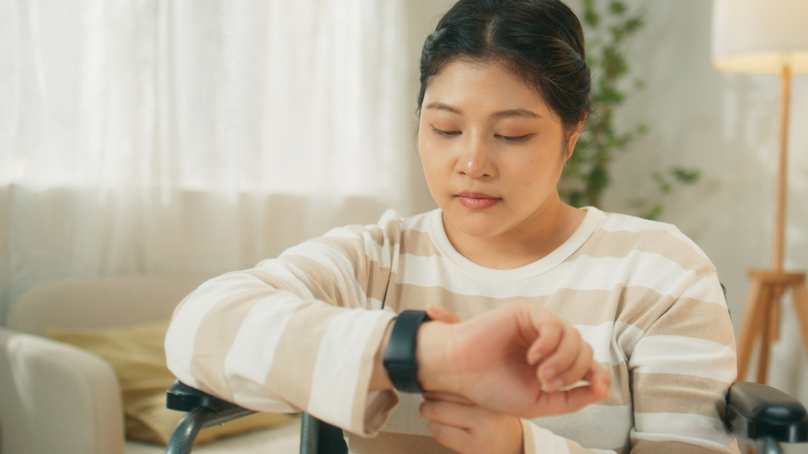 Young woman in a wheelchair checking their vital signs on a smart watch.