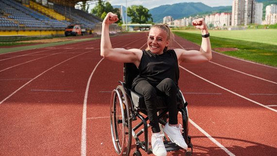Young woman with a disability in a wheelchair flexing her muscles.