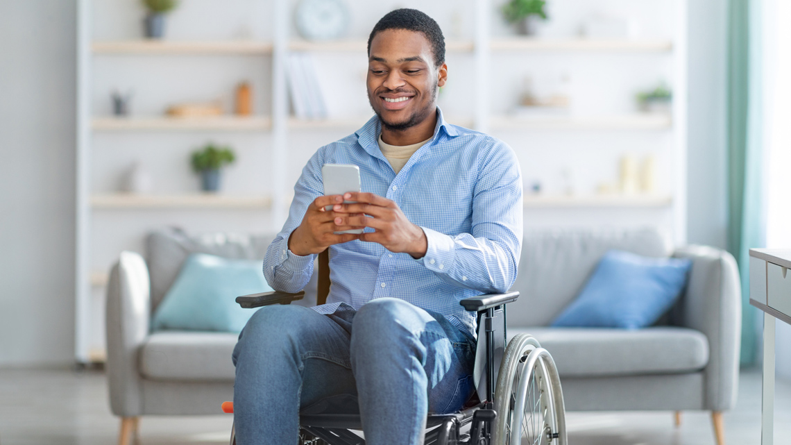 A young man in a wheelchair looking at his phone.
