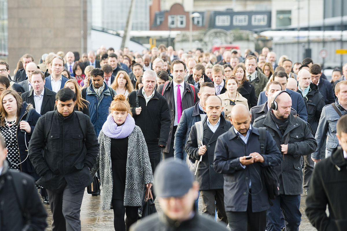 A crowd of people walking through a city street on a wet autumn day. 