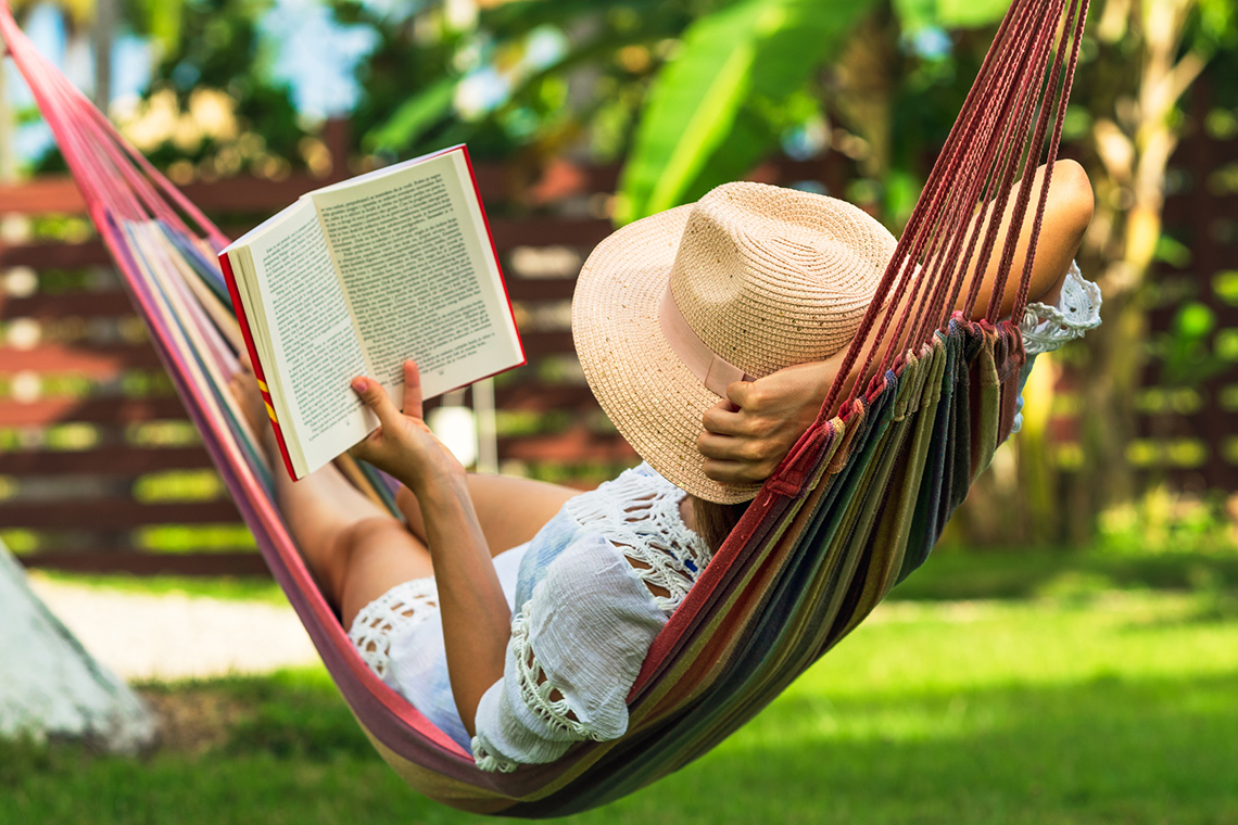 A person reading a book in a hammock