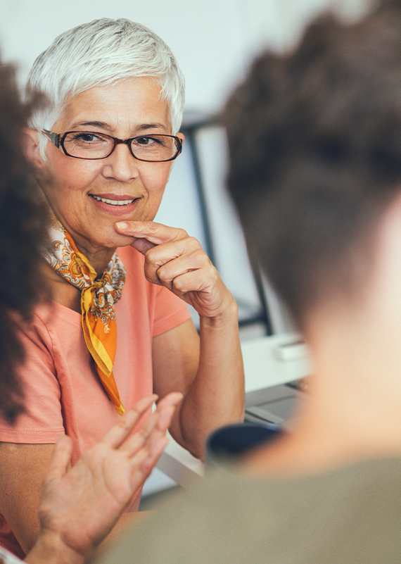 A person in conversation with someone. They are listening, smiling and making eye contact.