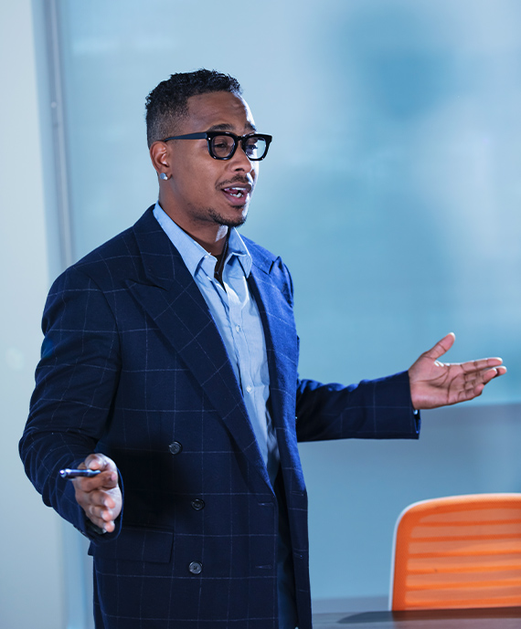 A confident person is speaking, looking relaxed. Their arms are open, hands are gesturing.
