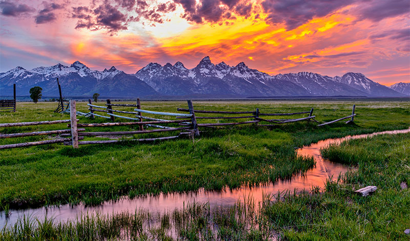 A colorful spring sunset at Teton Range, seen from an abandoned old ranch in Mormon Row historic district, in Grand Teton National Park, Wyoming, USA