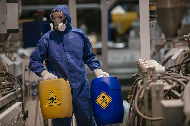 Worker wearing a respirator, protection suit, goggles and gloves while handling chemical substances