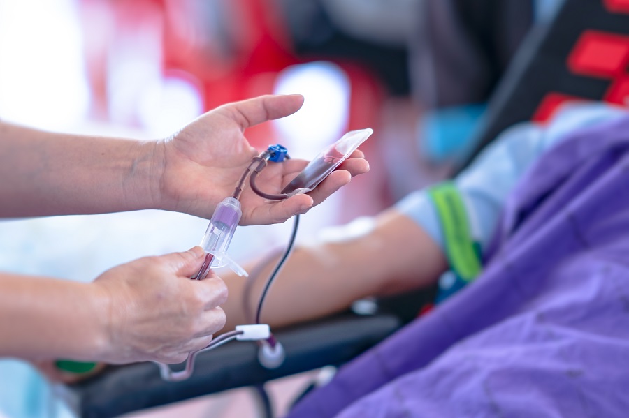 Someone wearing gloves, putting a needle into a patient’s arm to take blood