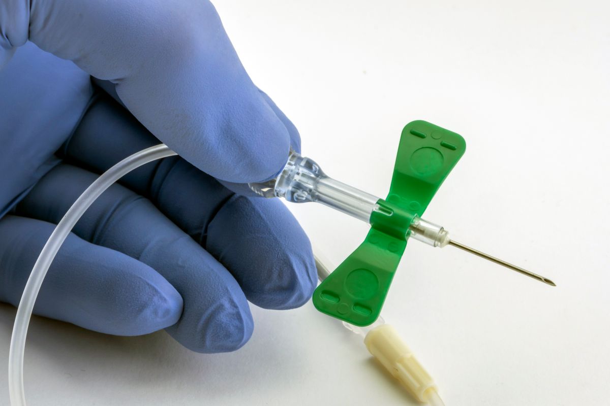 A needle that has small plastic pieces sticking out of either side and a tube running from it